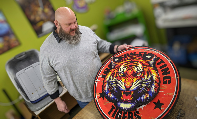 Sean Daniel is shown in his business working with a logo that features a Tiger