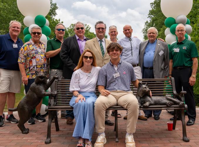 Family members and friends pose for a photo around one of the Bobcat Benches