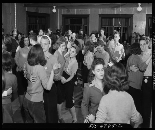 Old black-and-white photo of mixed-gender group of college students dancing in pairs