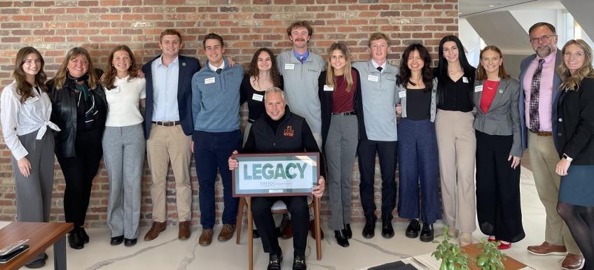 Tony Marino holds the Legacy Award while surrounded by OHIO students, faculty and staff