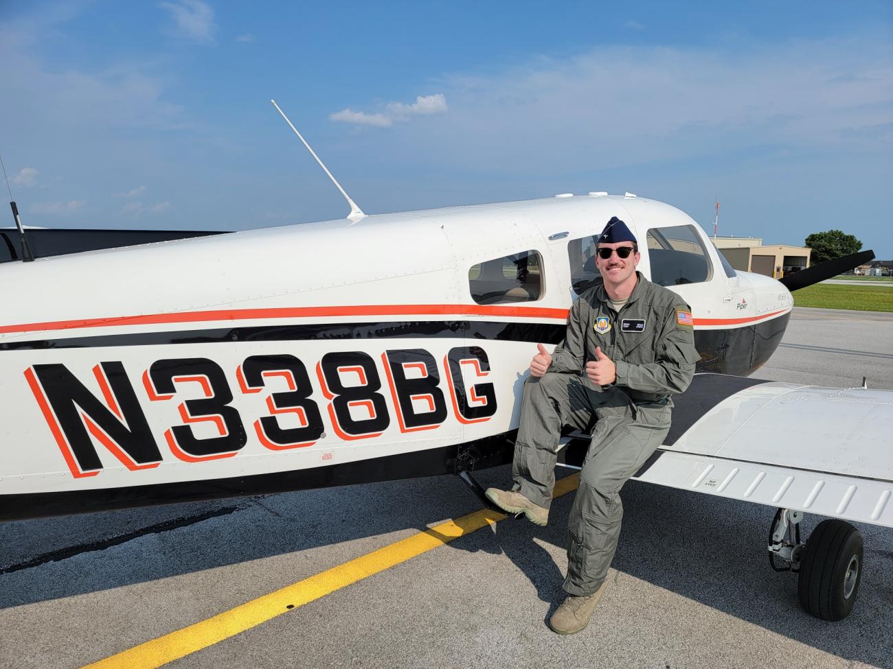 Griffin Braun leans against the wing of a small airplane 