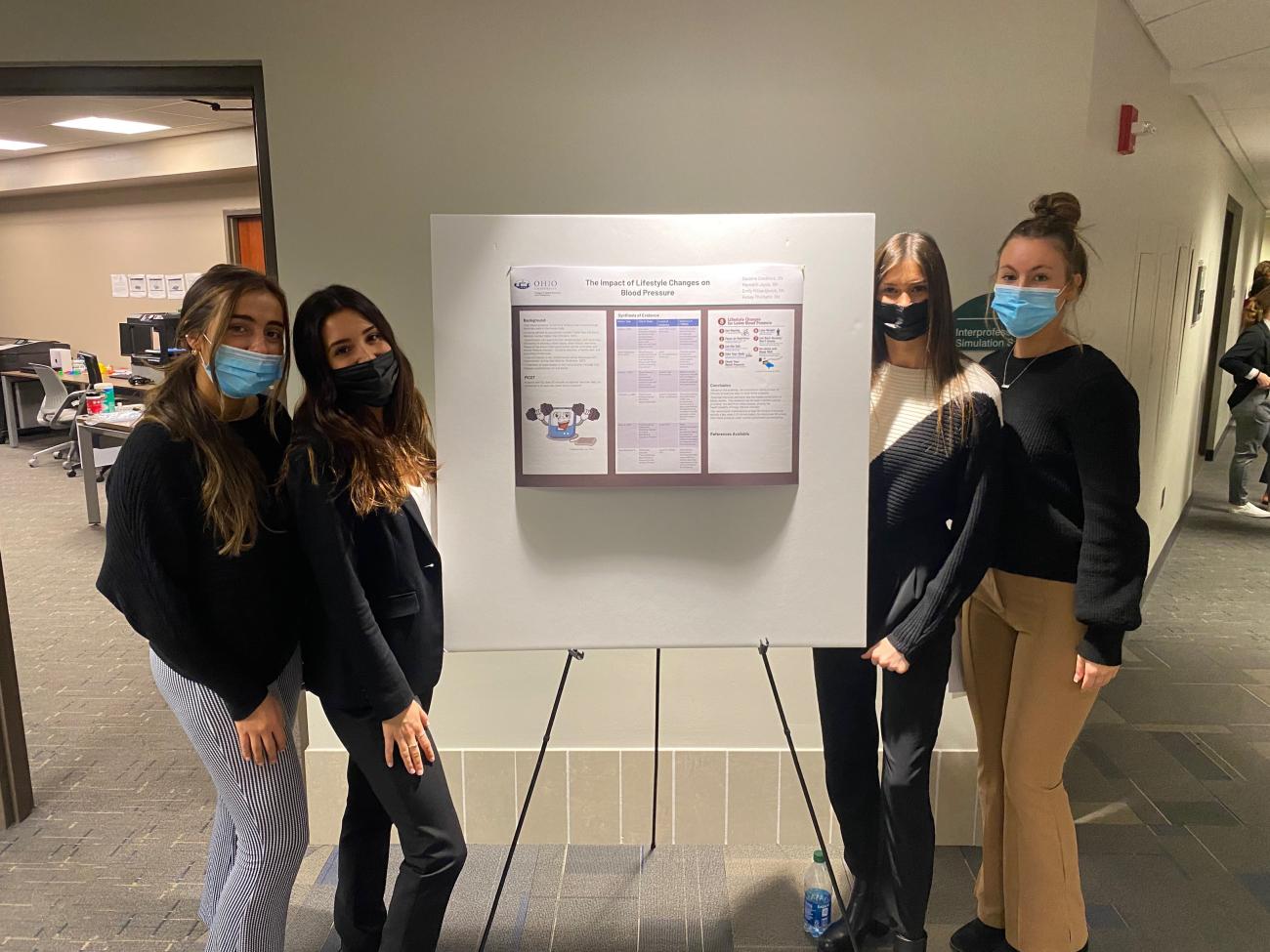 Students stand by their final project poster board