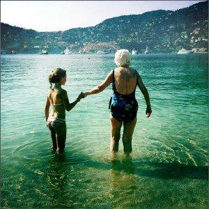 An old woman and a young girl stand in a lake holding hands