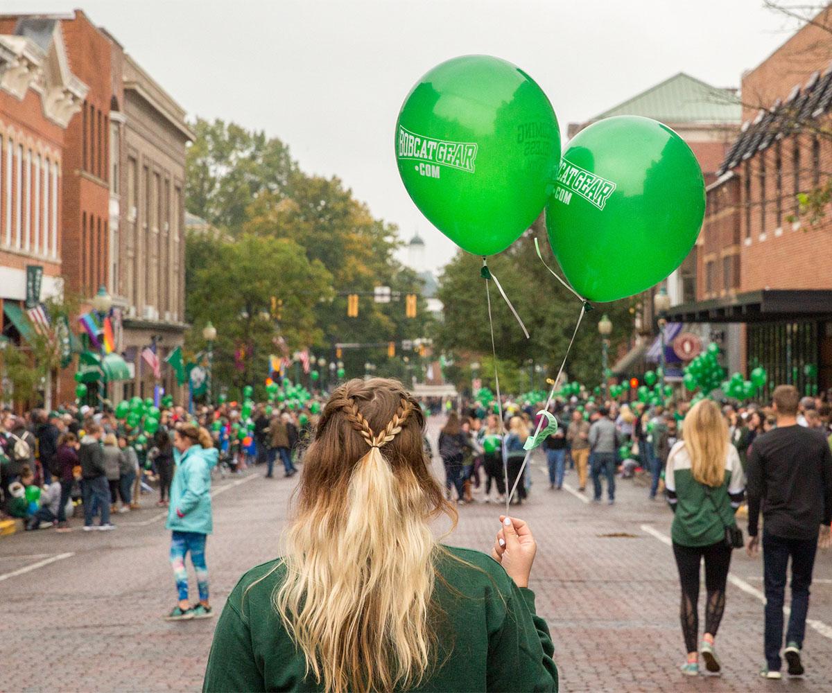 A student holds balloons at the Homecoming Parade.