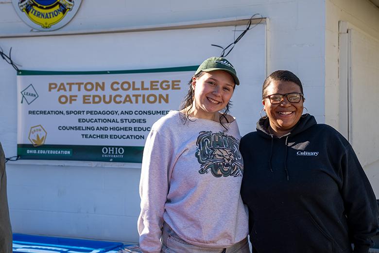 Two Patton College students pose in front of a Patton banner at this year's Stand Down.