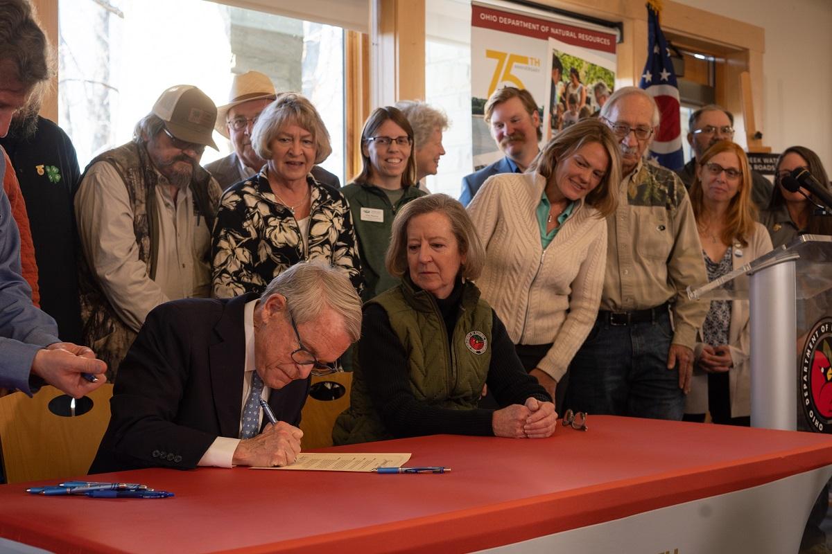 Gov. DeWine signs the official designation while a crowd of people look on