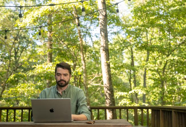 An OHIO student works on a computer while sitting outside