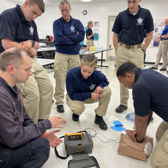 Chris Green Jr. practices skills with the automated external defibrillator while classmates observe