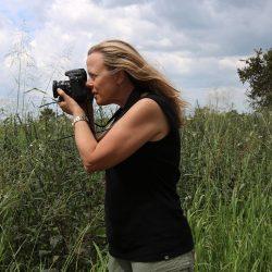 Portrait of Martha Rial taking a photo in a field of grass