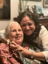 Two women pose for the camera, smiling and embracing