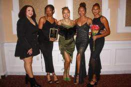 A group from the ABCD dance group poses for a photo, holding a plaque