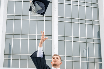 A graduate throws his cap in the air following Fall Commencement.