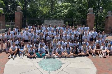 Participants in the High School Journalism Workshop are shown with members of The J Crew in front of the College Gate