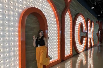 Allison Irey poses for a picture in front of a light-up "nick" sign at Nickelodeon Animation Studio