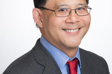 A professional photograph of a man in a suit and red tie