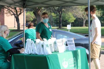 Nurses passing out bags of PPE at a tented location