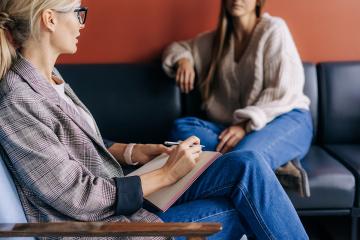 Psychology career option. A clinical psychology listening to a client during a session in an office