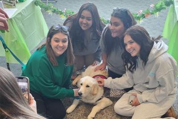 A group of women pose for a picture while petting a puppy