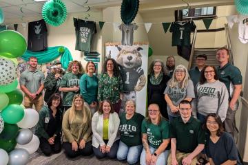 The members of the OHIO Business Service Center pose for a photo in an office decorated with green and white for Homecoming 2024