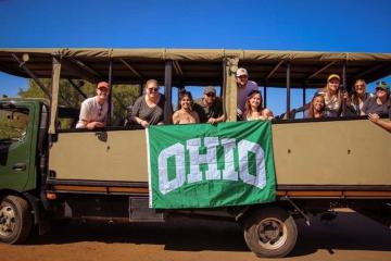 group of people posing in a safari van holding a OHIO flag