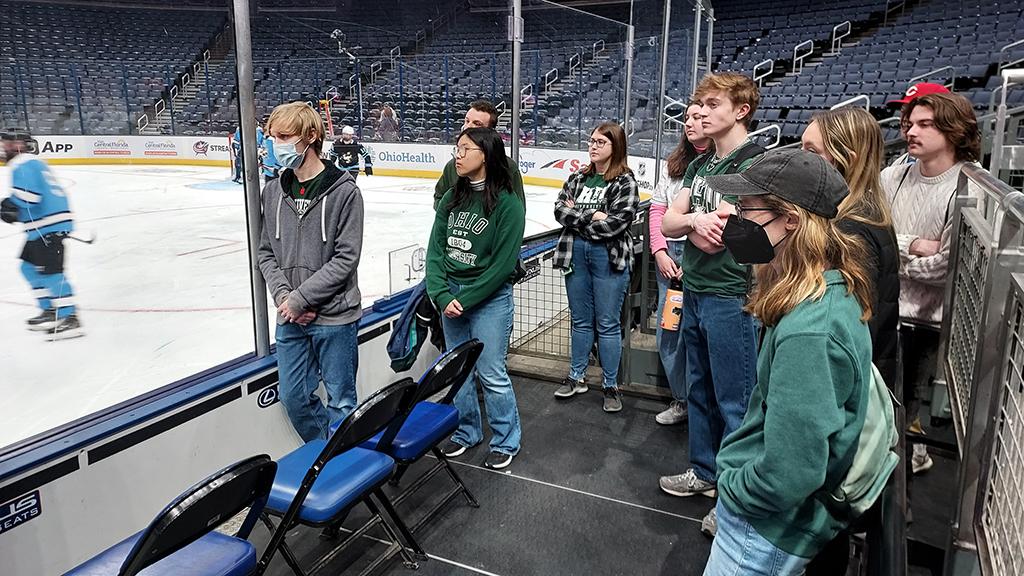 Student stand and watch hockey players in Columbus Blue Jackets arena