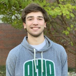 Jakob McElhaney smiles at the camera, wearing a grey hoodie with the word 'OHIO' in green across it.