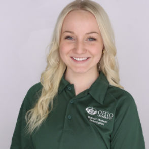 Regan in a dark green Bobcat Student Orientation shirt, smiling at the camera.