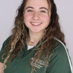 Nina in a dark green Bobcat Student Orientation shirt, smiling at the camera.