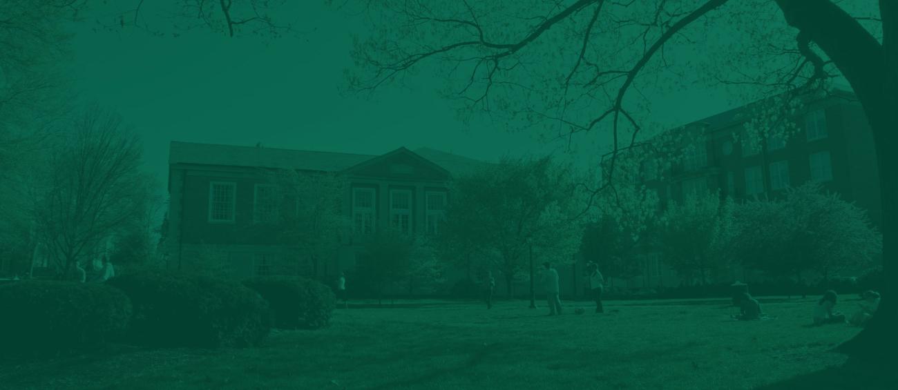 View of Ohio University's campus with students sitting in the grass and brick buildings in the background