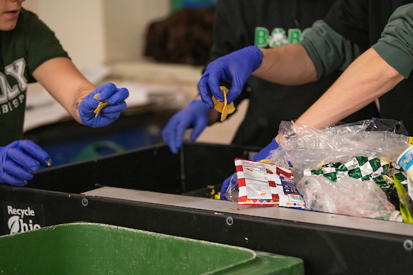 Recycling and Climate & Sustainability Ambassadors sort waste into compost, recycling and trash bins after a Bobcats basketball game.