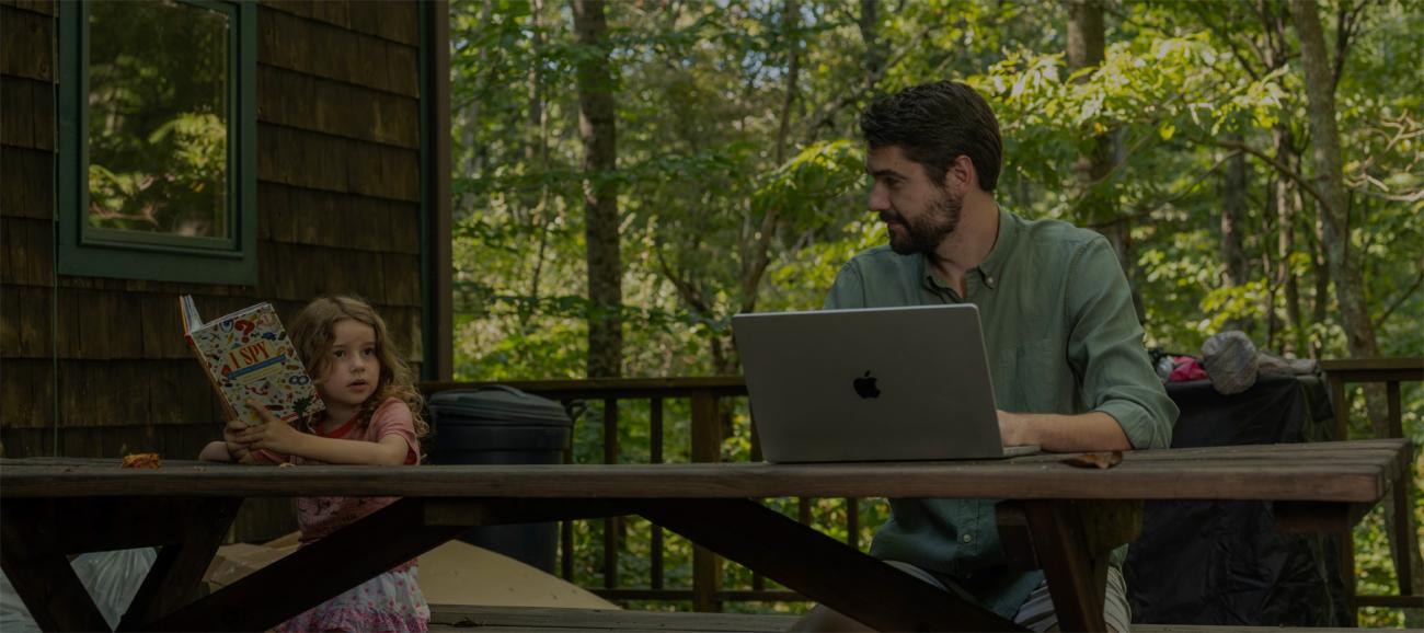 A family reads and works on a laptop outdoors