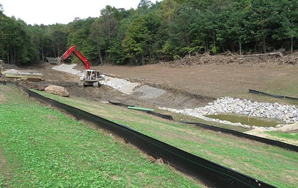 Large piece of construction equipment moving dirt in stream