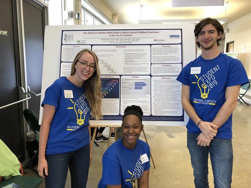 Three students in front of a poster at the Research Expo