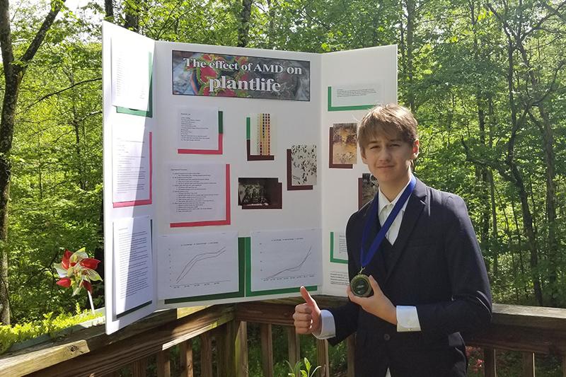 Miles Makosky stands in front of science fair poster